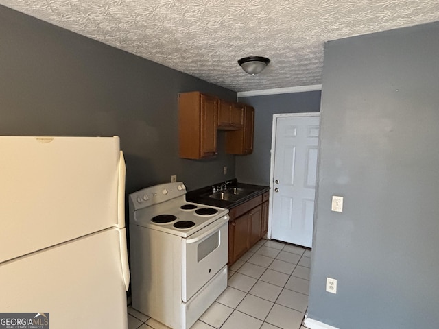 kitchen with sink, white appliances, a textured ceiling, and light tile patterned floors