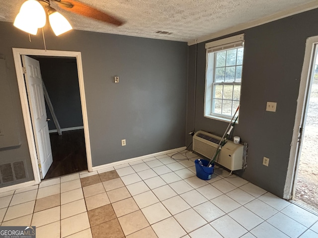 tiled empty room featuring ceiling fan and a textured ceiling