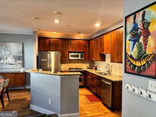 kitchen with light stone countertops, stainless steel appliances, crown molding, sink, and a kitchen island