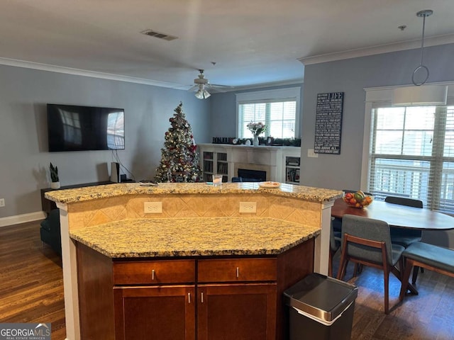 kitchen featuring light stone countertops, ceiling fan, dark hardwood / wood-style flooring, crown molding, and decorative light fixtures