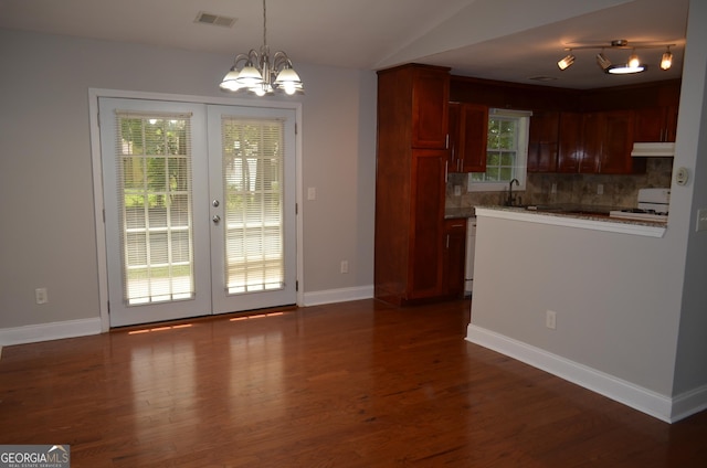 kitchen featuring french doors, an inviting chandelier, backsplash, vaulted ceiling, and white appliances