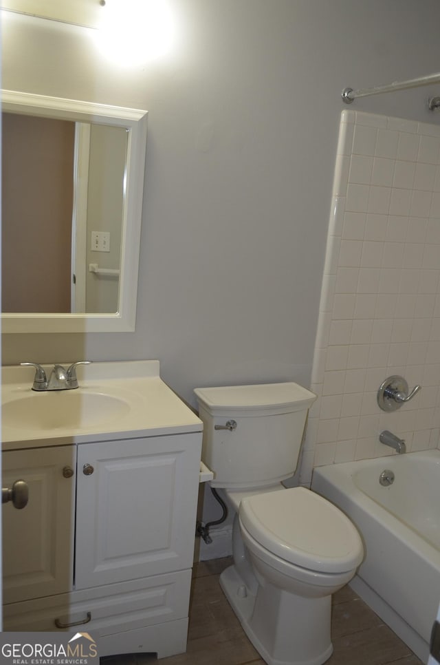 full bathroom with hardwood / wood-style floors, vanity, tiled shower / bath combo, and toilet