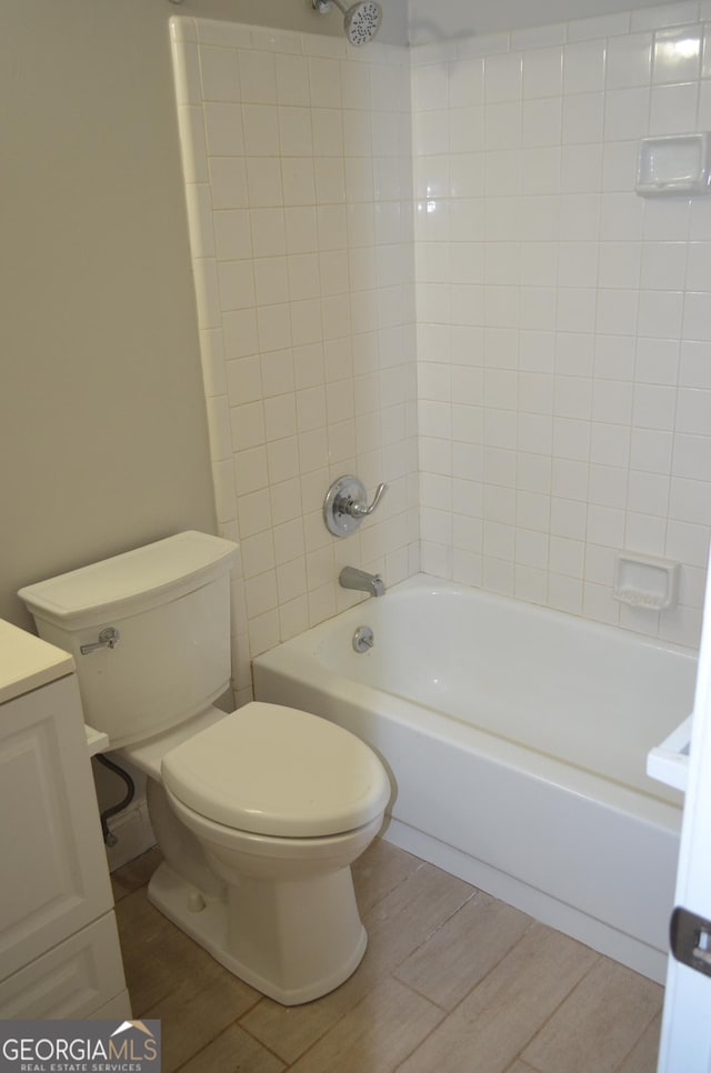 full bathroom featuring tiled shower / bath, vanity, and toilet