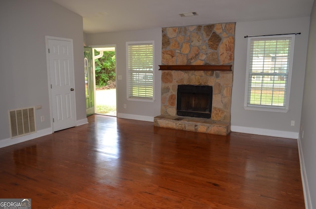 unfurnished living room with a fireplace, vaulted ceiling, and dark wood-type flooring