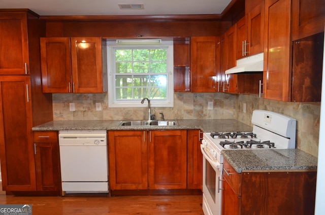 kitchen with decorative backsplash, light stone counters, sink, and white appliances