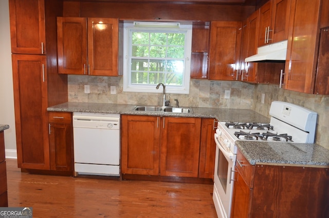 kitchen with hardwood / wood-style floors, white appliances, backsplash, sink, and light stone countertops