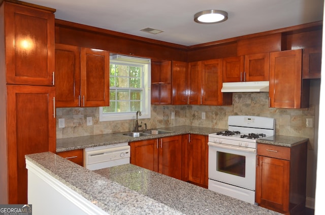 kitchen featuring decorative backsplash, light stone counters, sink, and white appliances