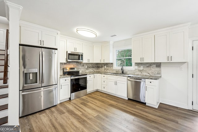 kitchen featuring appliances with stainless steel finishes, sink, dark stone countertops, and white cabinets