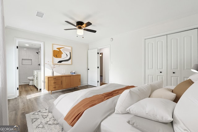 bedroom featuring ensuite bathroom, wood-type flooring, ceiling fan, crown molding, and a closet