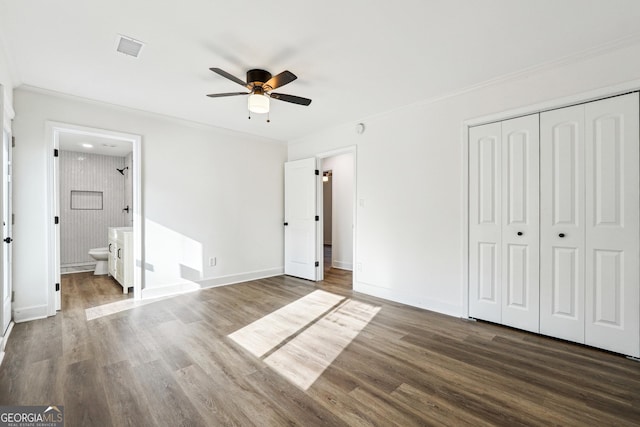 unfurnished bedroom with ceiling fan, dark hardwood / wood-style floors, ensuite bathroom, ornamental molding, and a closet