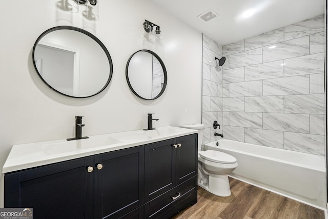 full bathroom featuring vanity, hardwood / wood-style flooring, toilet, and tiled shower / bath