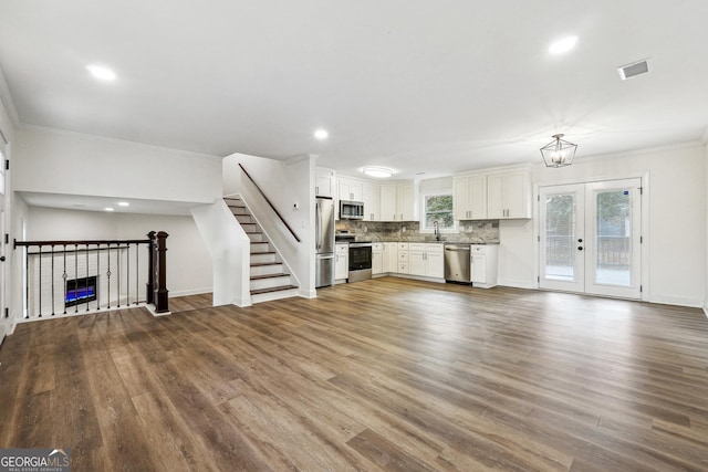 unfurnished living room featuring sink, wood-type flooring, ornamental molding, and french doors