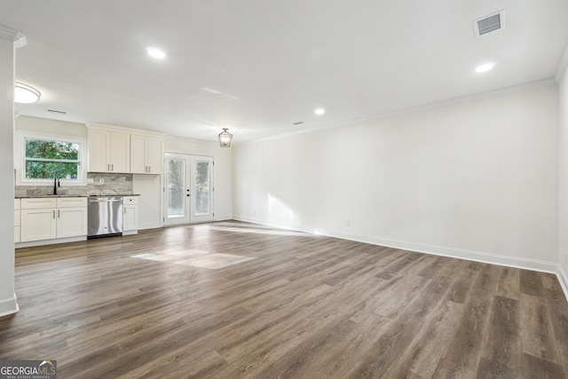 unfurnished living room featuring sink, hardwood / wood-style flooring, ornamental molding, and french doors