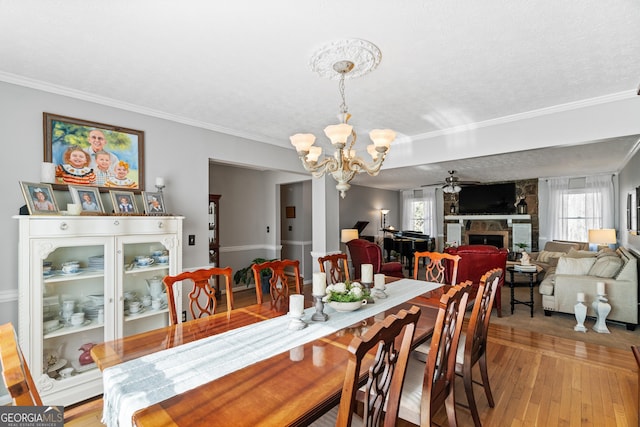 dining space with a textured ceiling, ceiling fan with notable chandelier, a fireplace, and a wealth of natural light