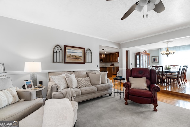 living room featuring a textured ceiling, ceiling fan with notable chandelier, and crown molding