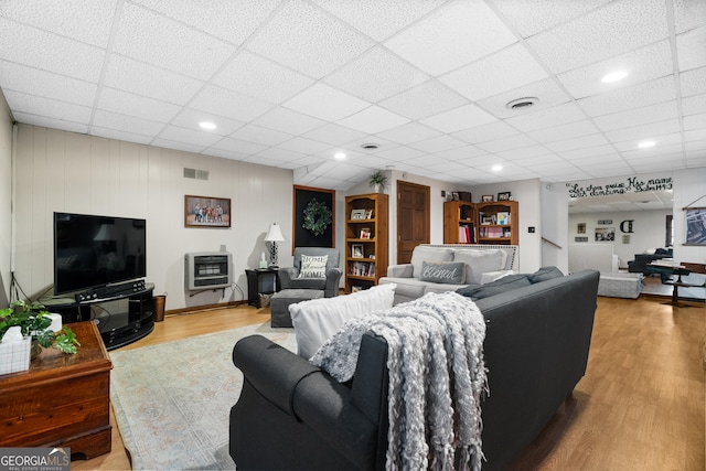 living room featuring a paneled ceiling, wood-type flooring, and heating unit