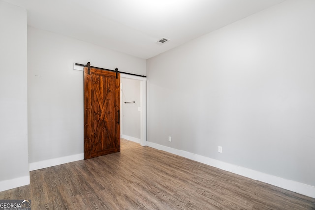 spare room with a barn door and hardwood / wood-style flooring