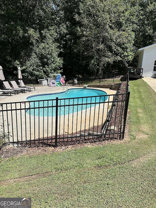 view of pool with a patio area, a diving board, and a yard