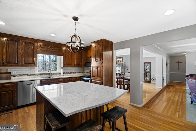 kitchen with pendant lighting, a center island, sink, decorative backsplash, and stainless steel appliances