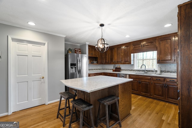 kitchen with a center island, sink, light hardwood / wood-style flooring, tasteful backsplash, and decorative light fixtures