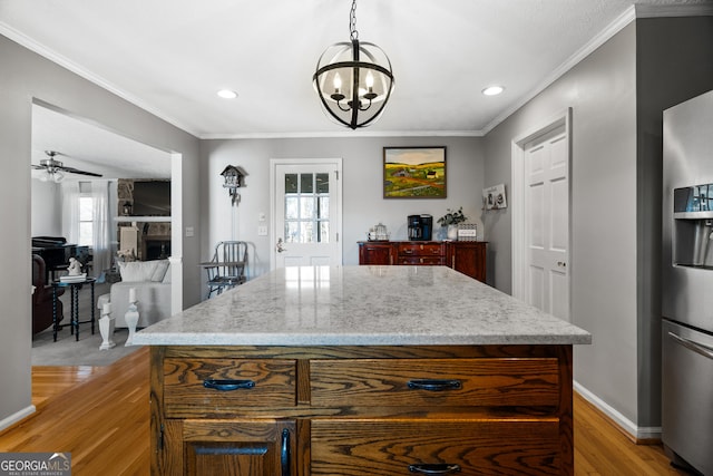 kitchen with stainless steel refrigerator with ice dispenser, decorative light fixtures, and a kitchen island