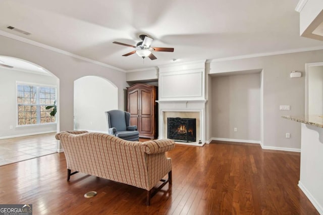 living room with a premium fireplace, ceiling fan, dark hardwood / wood-style flooring, and crown molding