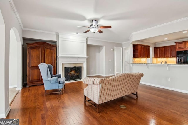 living room featuring a fireplace, ceiling fan, dark hardwood / wood-style flooring, and ornamental molding