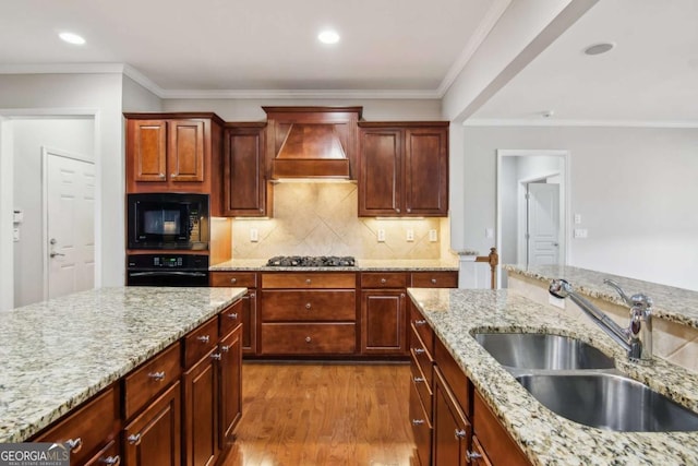 kitchen featuring premium range hood, light stone counters, black appliances, and sink