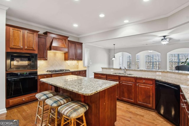 kitchen featuring sink, premium range hood, crown molding, a breakfast bar area, and black appliances