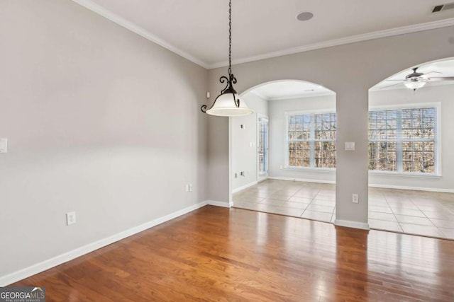 unfurnished dining area featuring ceiling fan, crown molding, and light tile patterned floors