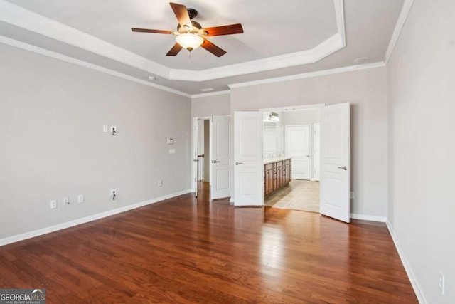 unfurnished bedroom with ceiling fan, wood-type flooring, and a tray ceiling