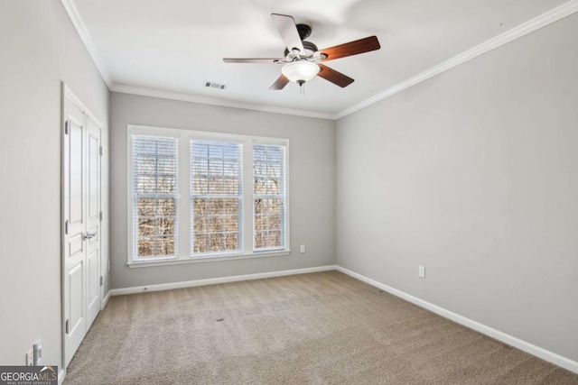 empty room with carpet flooring, ceiling fan, and crown molding