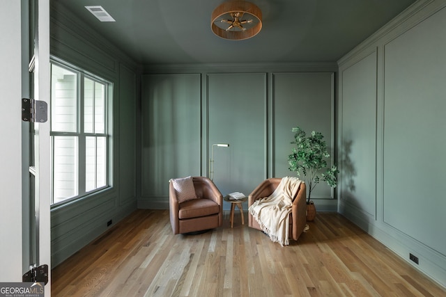 living area with light hardwood / wood-style flooring and ornamental molding