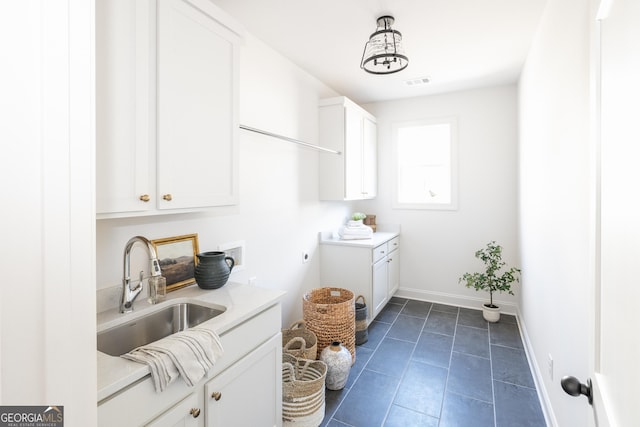 laundry area with cabinets, electric dryer hookup, sink, and dark tile patterned floors