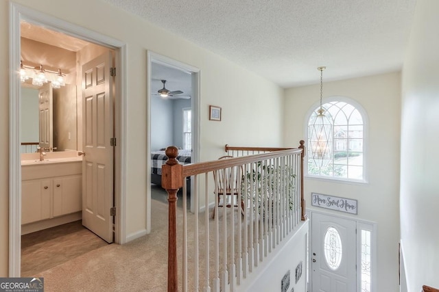 interior space featuring ceiling fan, light colored carpet, sink, and a textured ceiling