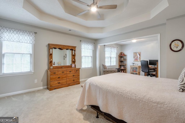 bedroom with ceiling fan, carpet flooring, and a tray ceiling