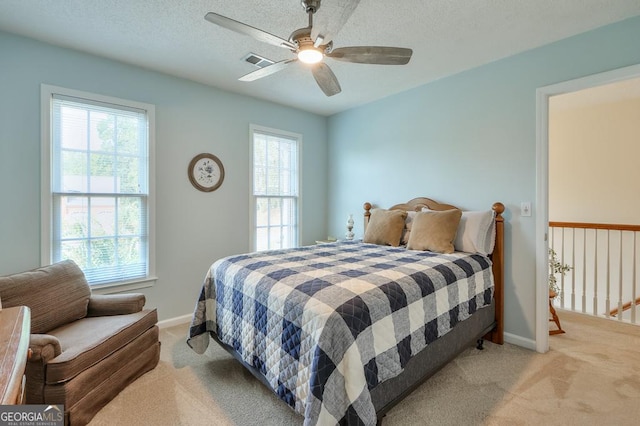 bedroom with multiple windows, a textured ceiling, ceiling fan, and light colored carpet