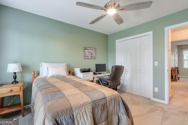 bedroom featuring light colored carpet, ceiling fan, and a closet