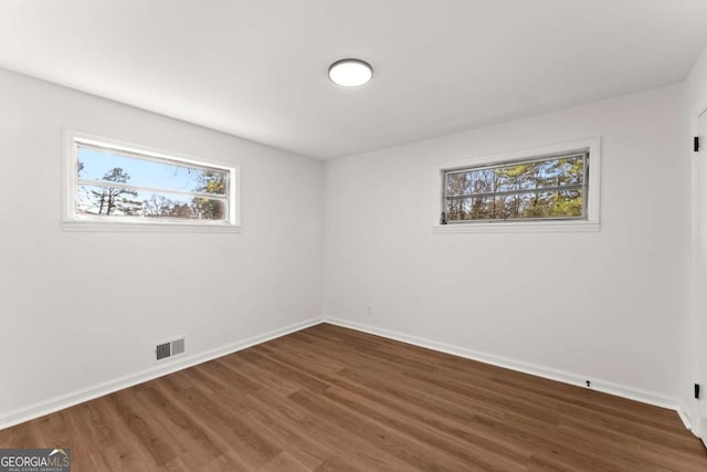 unfurnished room featuring a healthy amount of sunlight and dark hardwood / wood-style floors