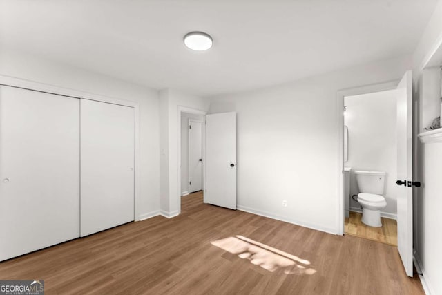 unfurnished bedroom featuring connected bathroom, light hardwood / wood-style flooring, and a closet