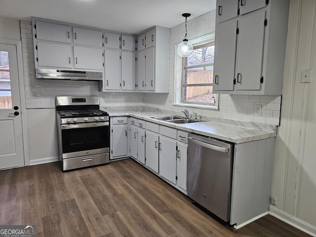 kitchen with appliances with stainless steel finishes, light hardwood / wood-style flooring, pendant lighting, and sink