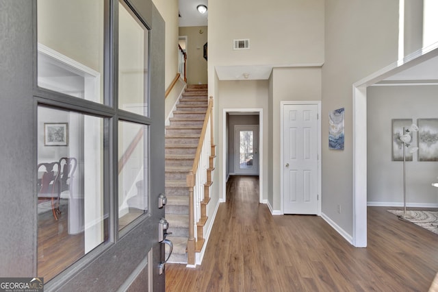 entryway featuring dark hardwood / wood-style flooring and a towering ceiling