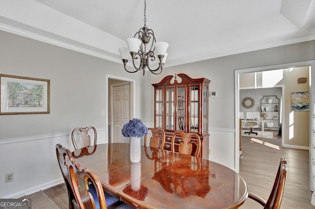 dining space with a textured ceiling, hardwood / wood-style flooring, crown molding, and a notable chandelier