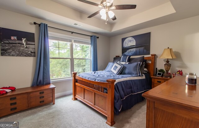 carpeted bedroom featuring a tray ceiling and ceiling fan