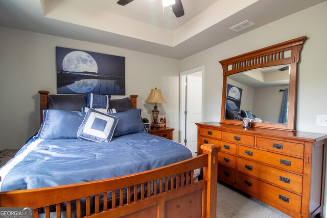 carpeted bedroom featuring a raised ceiling and ceiling fan