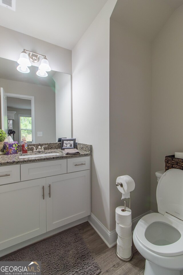 bathroom featuring wood-type flooring, vanity, and toilet