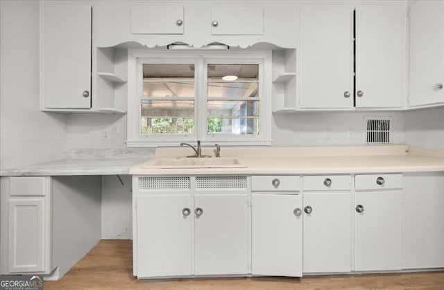 kitchen featuring tasteful backsplash, white cabinetry, light hardwood / wood-style floors, and sink