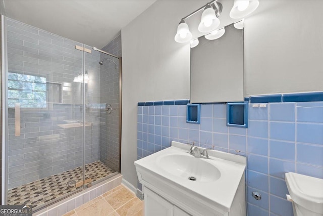 bathroom with tile patterned floors, an enclosed shower, vanity, tile walls, and toilet