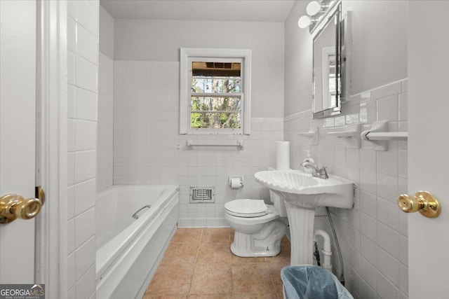 bathroom with tile patterned flooring, a bathtub, toilet, and tile walls