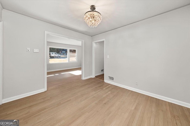 spare room with light hardwood / wood-style floors and an inviting chandelier